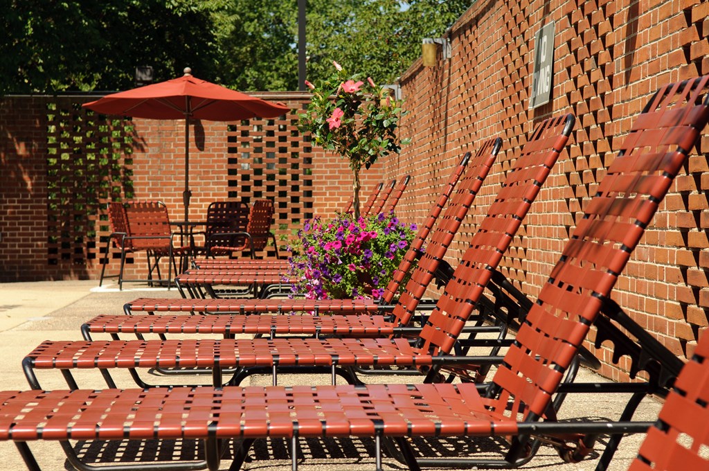 A row of red chairs are lined up on a patio.