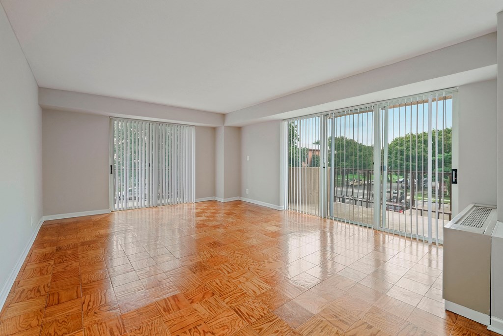 A room with a wood floor and a window with blinds.