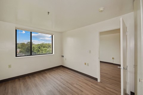 an empty living room with wood floors and a large window