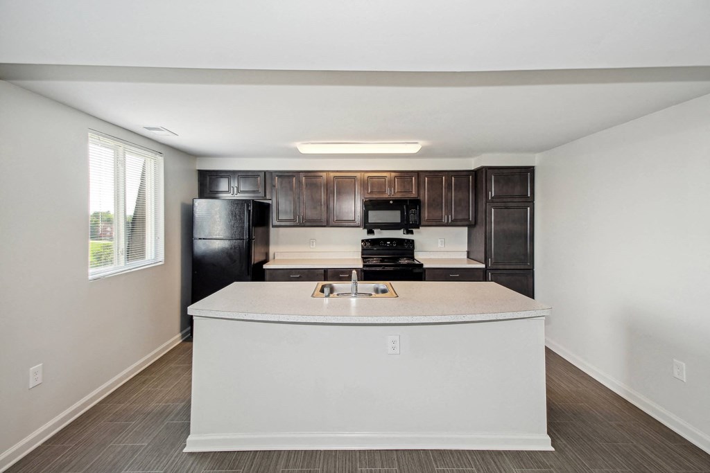 a kitchen with a white counter top and a black refrigerator