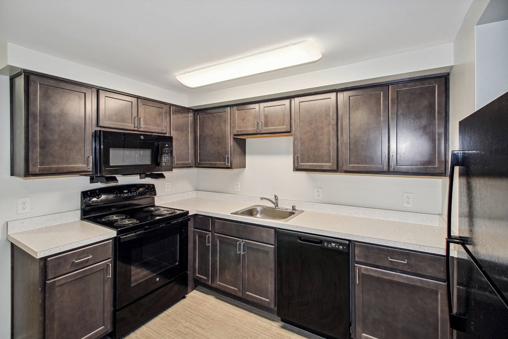 a kitchen with black appliances and dark wood cabinets