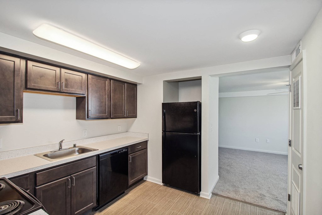 a kitchen with dark wood cabinets and a black refrigerator