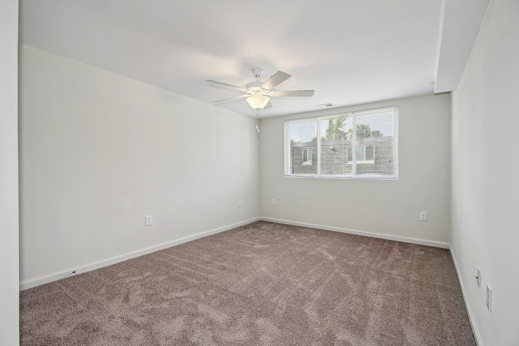 an empty living room with a ceiling fan and a window