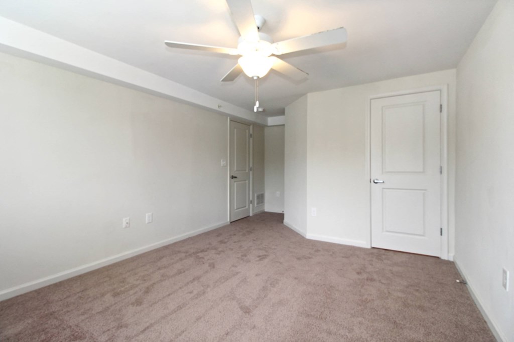 an empty living room with white walls and a ceiling fan