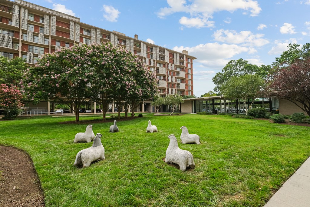 a group of geese in the grass in front of an apartment building