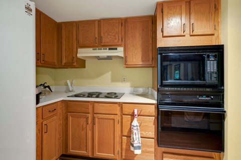 A kitchen with wooden cabinets and a black microwave.