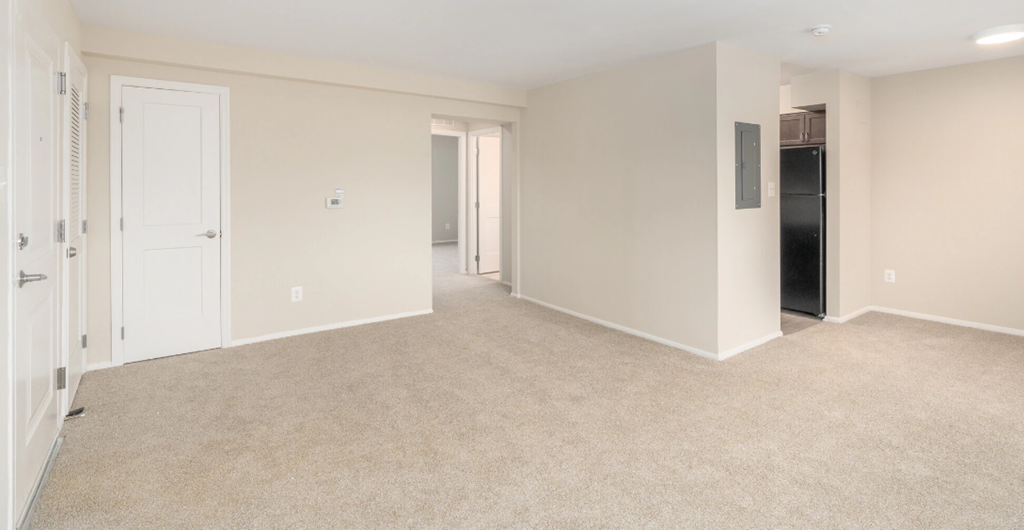 an empty living room with a door to a hallway and a closet