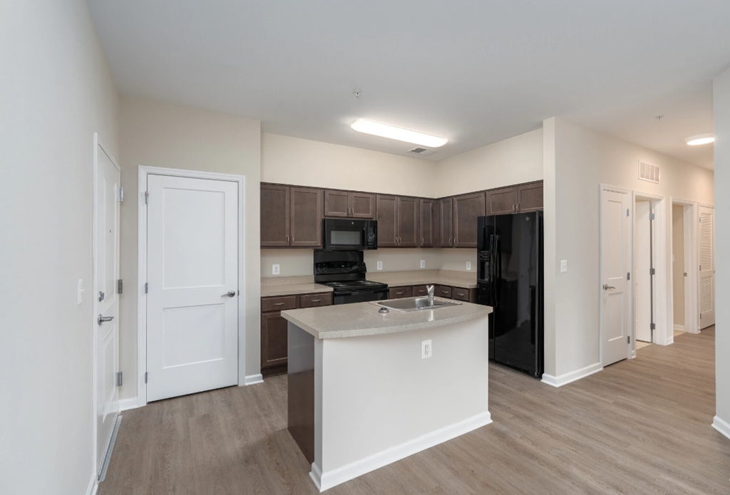 a kitchen with an island and a black refrigerator