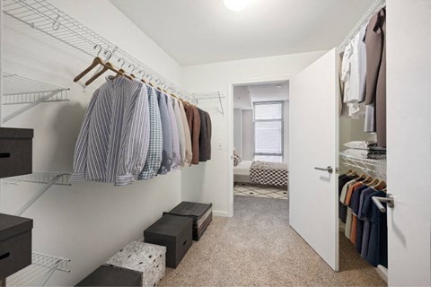 a walk in closet with clothes hanging on a rack