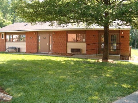A red brick house with a tree in front.