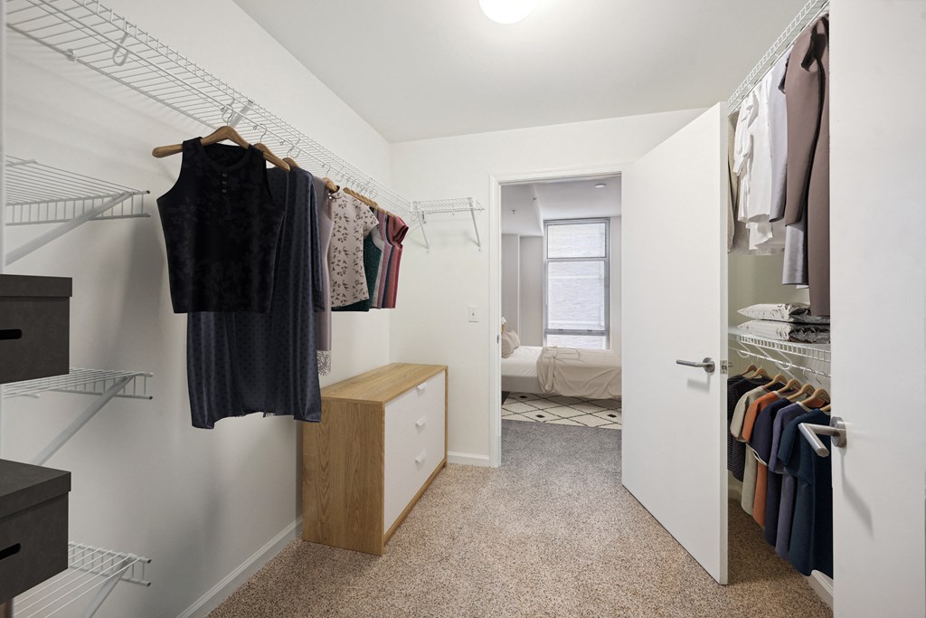 a walk in closet with clothes hanging on a rack and a door to a bedroom