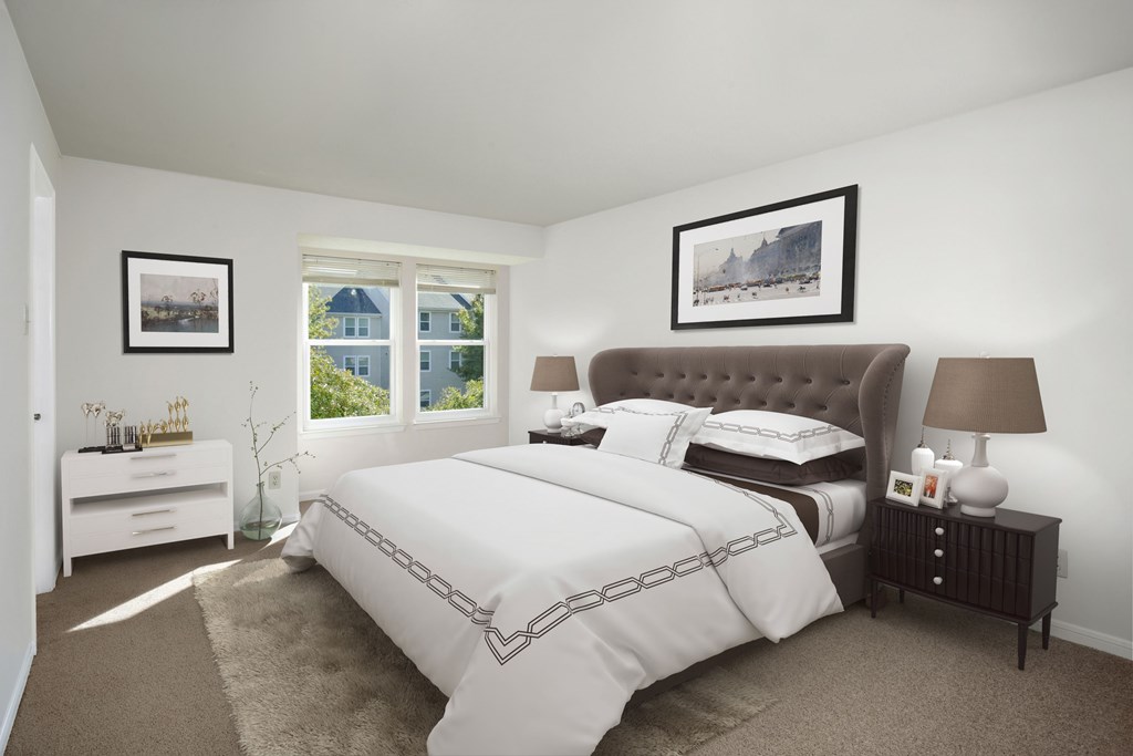 A bedroom with a large bed and a window overlooking a blue house.