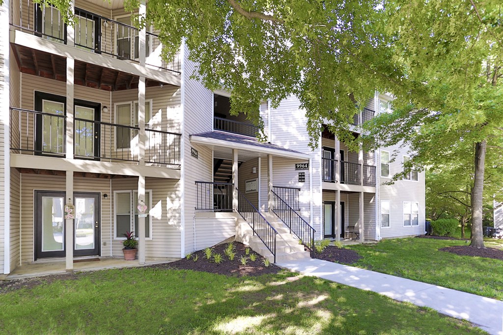 A white apartment building with a tree in front.