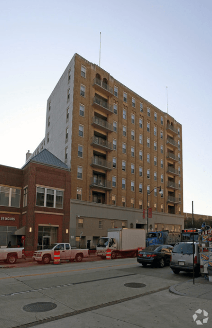 A tall building with a flat roof and a parking lot in front of it.