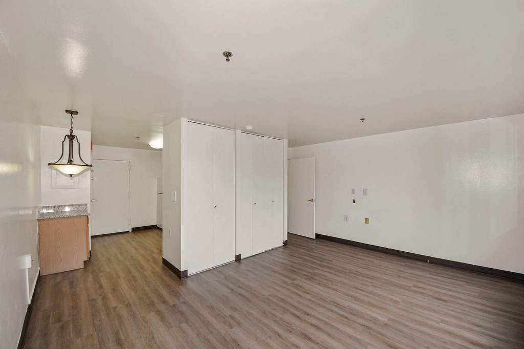 the living room and kitchen of an empty house with white walls and wood floors
