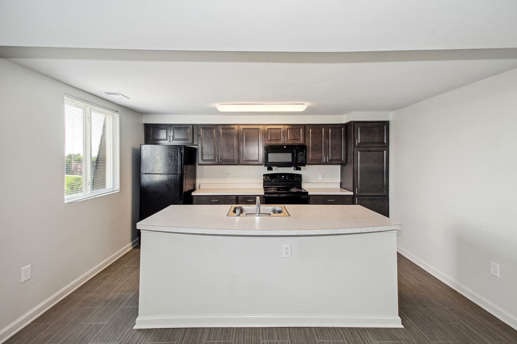 an empty kitchen with a counter top and a refrigerator