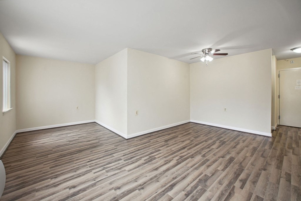 an empty living room with wood flooring and a ceiling fan