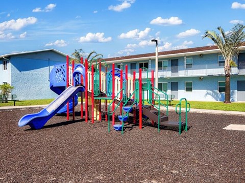 A playground with a blue slide and red and green climbing structures.