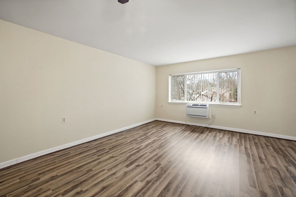 an empty living room with wood floors and a window