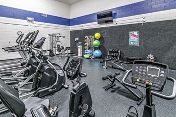 a gym with cardio equipment and weights on the floor