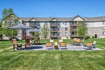 an outdoor patio with chairs and umbrellas with an apartment building in the background