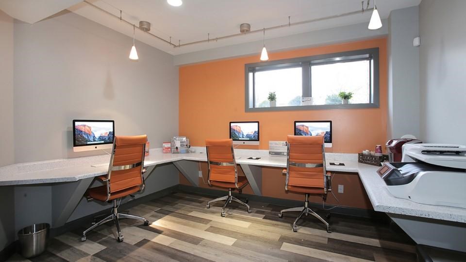 A room with orange walls and a desk with a computer and a monitor.