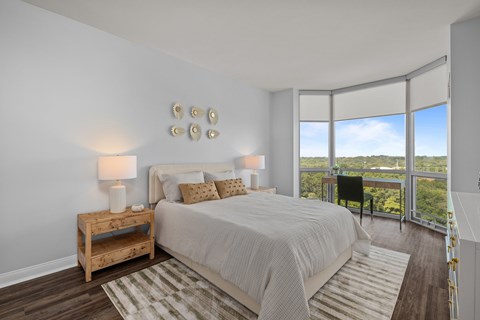 A bedroom with a large bed and a view of the outdoors through the window at Clayton on the Park Apartments, Missouri, 63105