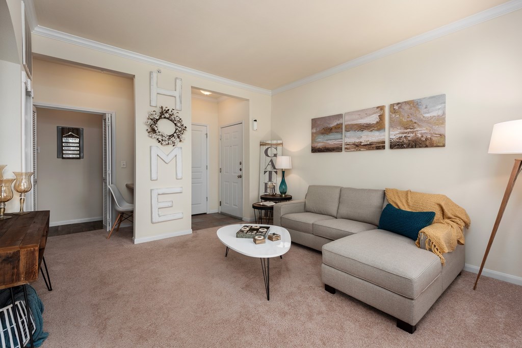A living room with a grey couch, a coffee table, and a wreath on the door.