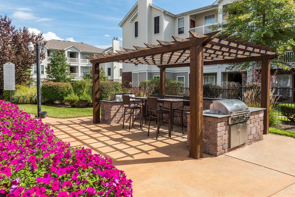 A patio with a grill and a pergola.