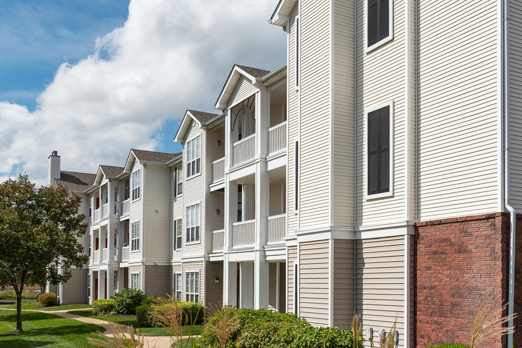 A row of apartment buildings with balconies and a brick column.