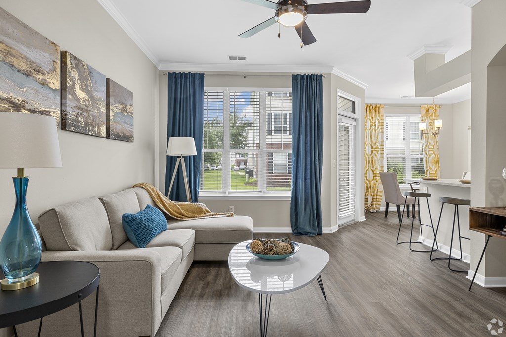 A living room with a couch, a table, and a ceiling fan.