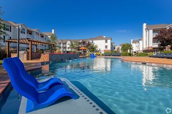 A swimming pool with blue loungers and a clear sky.
