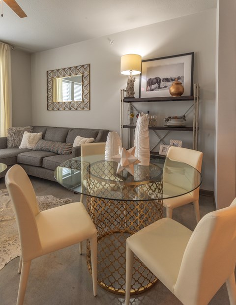 A modern dining room with a glass table and chairs.