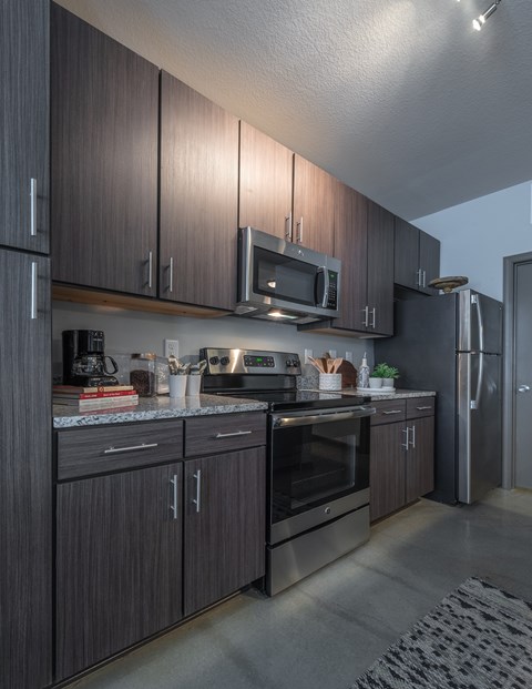 A modern kitchen with dark wood cabinets and stainless steel appliances.