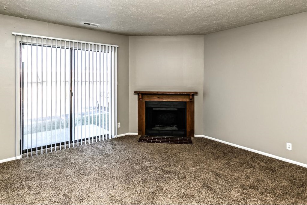 an empty living room with a fireplace and a sliding glass door