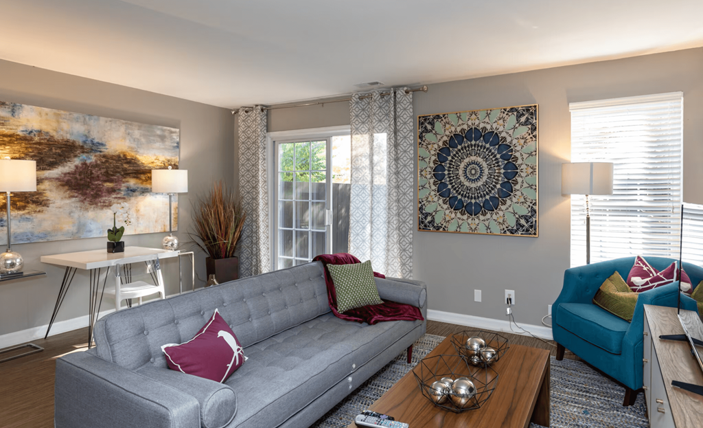 A living room with a grey couch and a large tapestry on the wall.