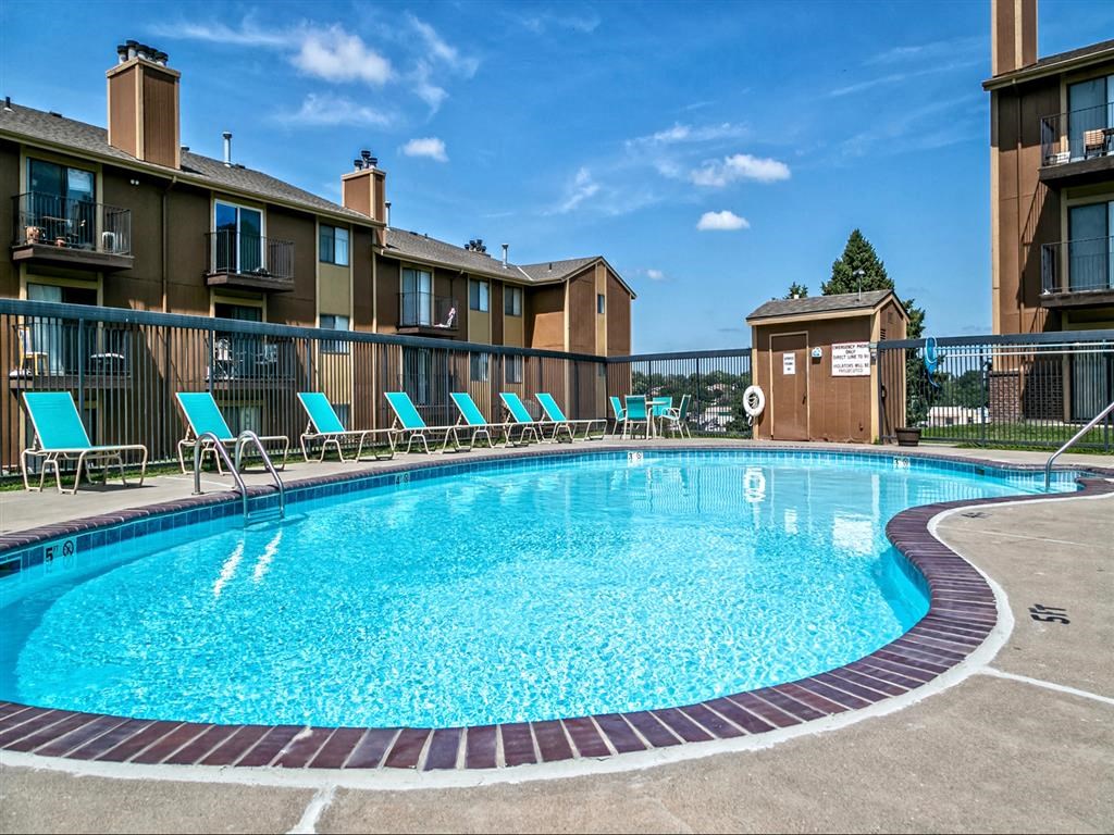 a resort style pool with blue chairs and apartments in the background