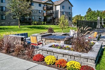 a backyard with a fire pit and patio with chairs and flowers