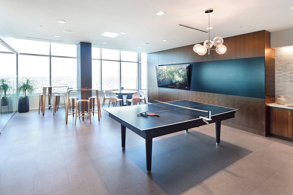 A ping pong table is in the middle of a room with a tv and a bar at Two Twelve Clayton Apartments, Clayton, Missouri