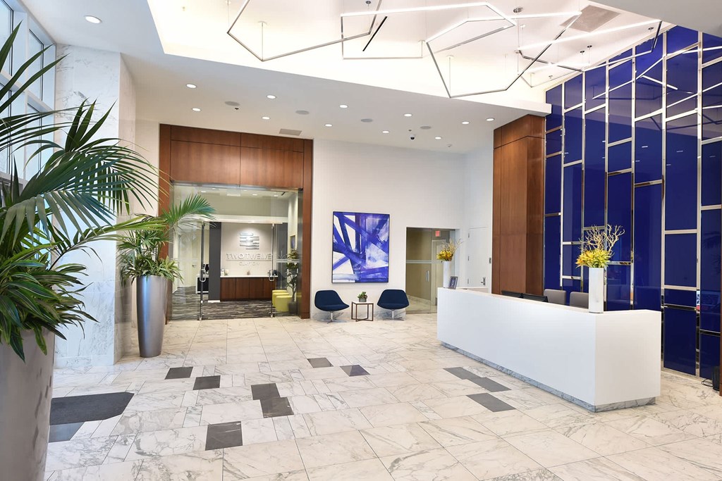 A reception area with a white reception desk and a blue wall at Two Twelve Clayton Apartments, Missouri