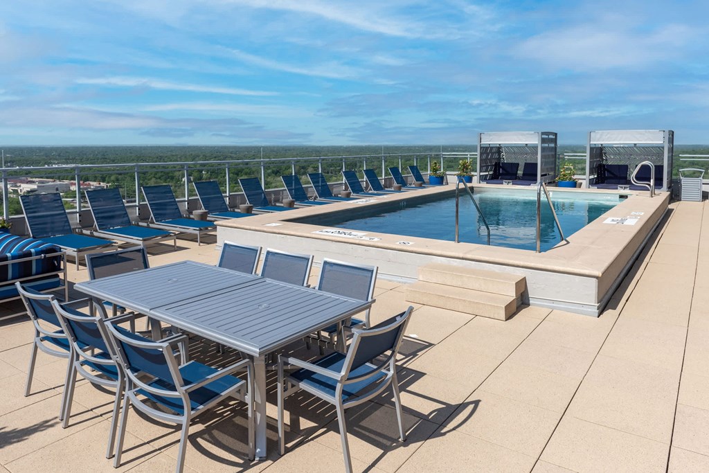 A table and chairs are set up on a patio overlooking a pool at Two Twelve Clayton Apartments, Clayton, MO