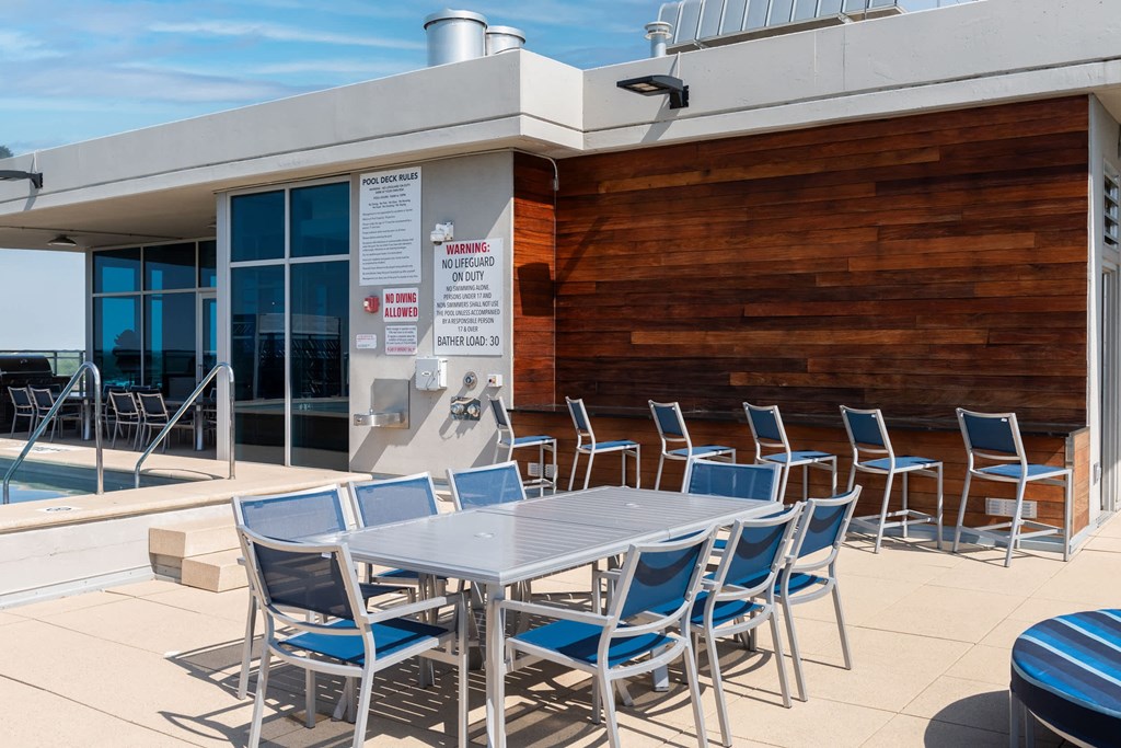 A poolside table with chairs and a warning sign on the wall at Two Twelve Clayton Apartments, Missouri