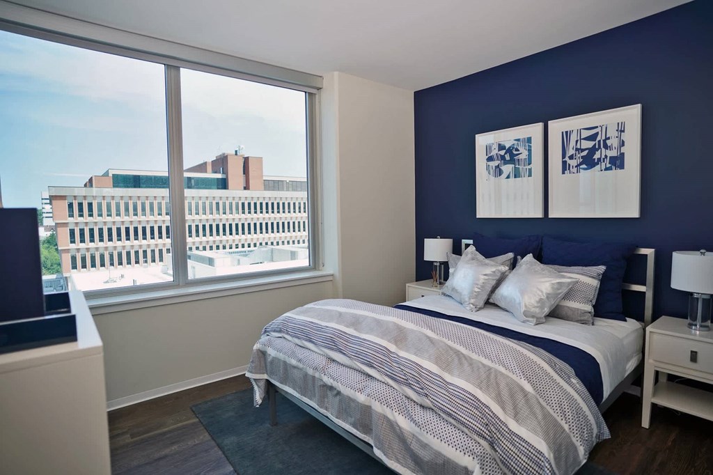 A bedroom with a large bed and a view of the city at Two Twelve Clayton Apartments, Clayton, MO, 63105