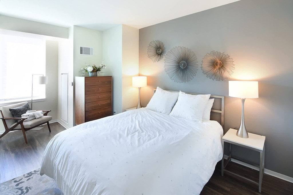 A bedroom with a large bed and a chair by the window at Two Twelve Clayton Apartments, Clayton