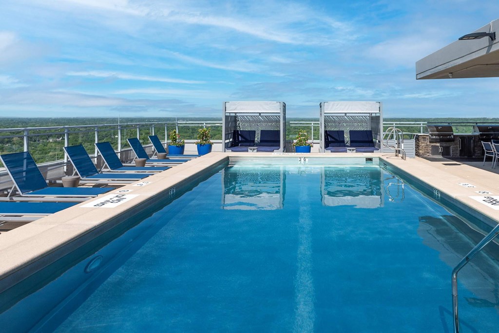 A large outdoor swimming pool with lounge chairs and a view of the horizon at Two Twelve Clayton Apartments, Missouri