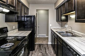the kitchen of a home with black appliances and wood cabinets