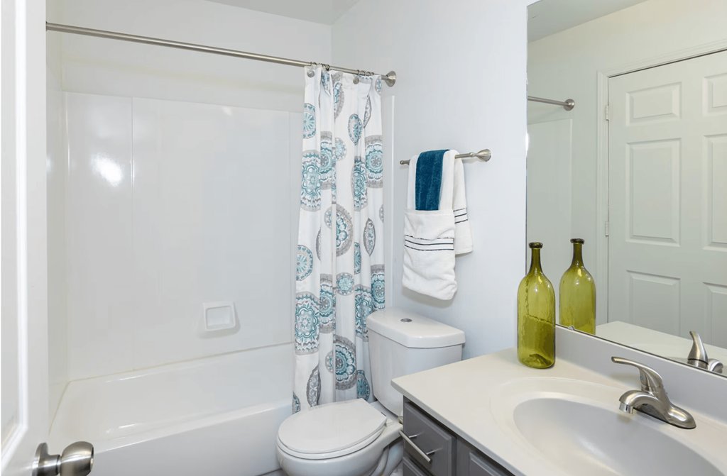 A white bathroom with a toilet, sink, and shower curtain.