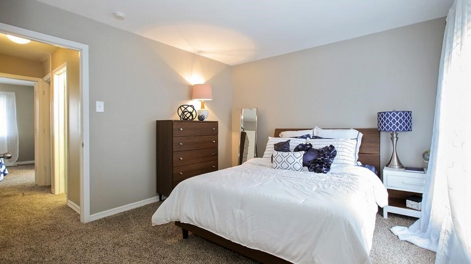 A bedroom with a bed, nightstand, and lamp.