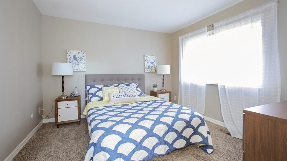 A bedroom with a bed, two lamps, and a nightstand.