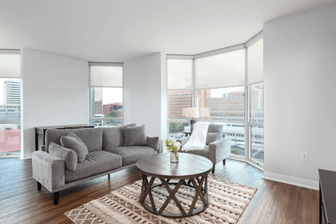 A living room with a grey couch, a coffee table and a large window.
